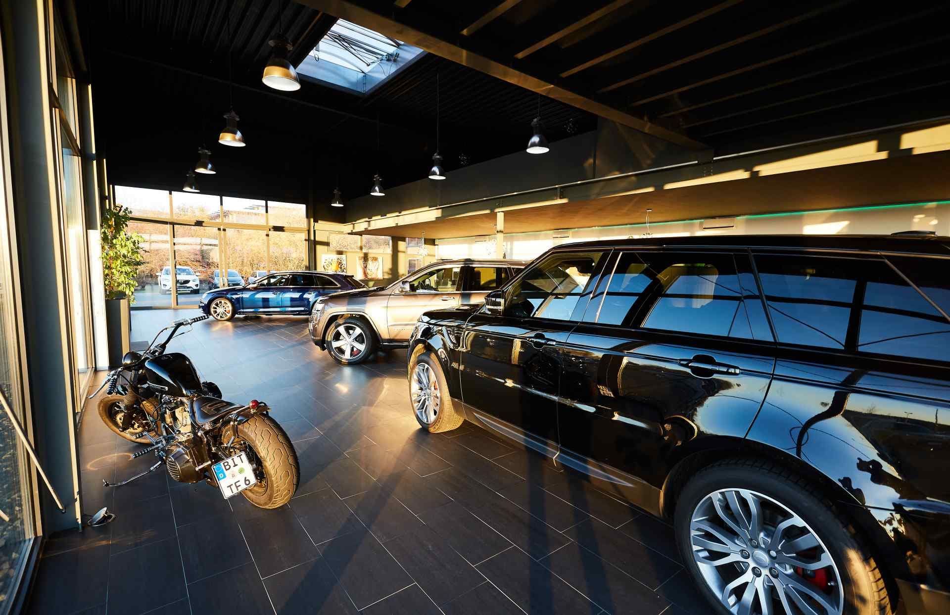 A wide view of the showroom with a motorcycle and a Range Rover