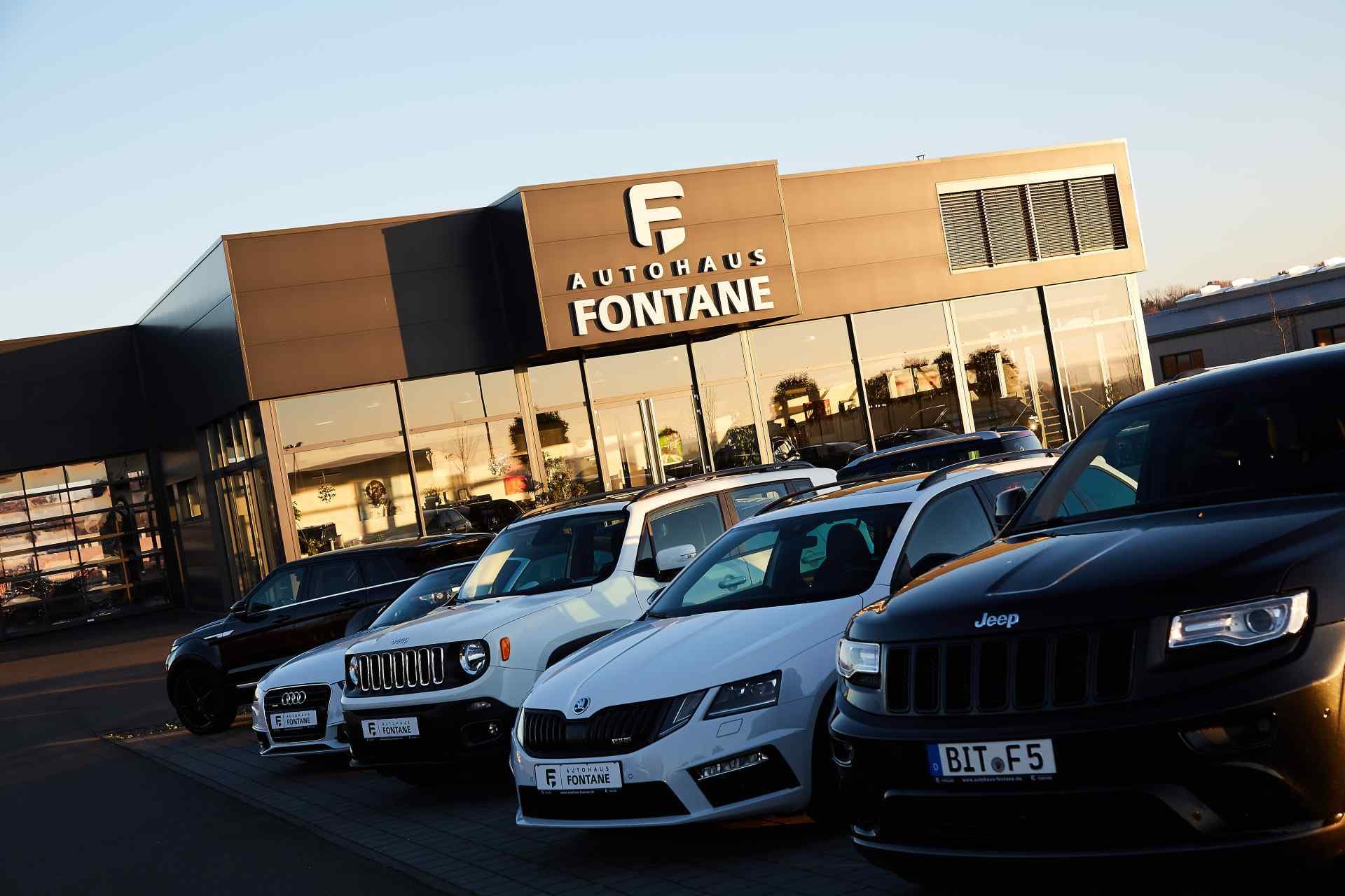 The Autohaus Fontane building at golden hour, with vehicles lined up in front