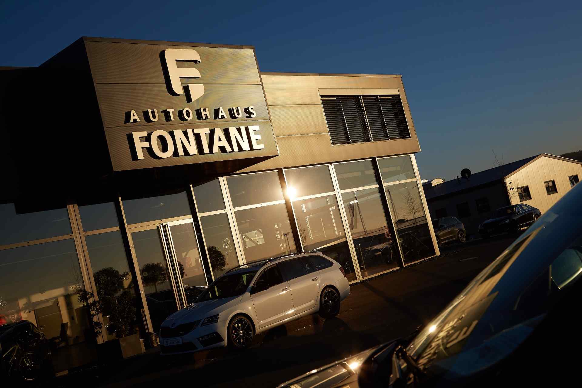 The illuminated Autohaus Fontane sign above the showroom at dusk